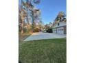 Spacious driveway leading to a two-car garage, set against a backdrop of tall trees at 202 Woodland Dr, Summerville, SC 29485