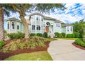 Beautiful exterior of a light green home with a well-manicured lawn and mature landscaping at 24 Waterway Island Dr, Isle of Palms, SC 29451