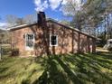 View of the rear of a brick house with green grass and large shade trees at 431 Otis Rd, Walterboro, SC 29488