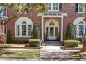 Elegant brick home featuring an arched entrance, trimmed hedges, and a manicured lawn at 56 Parkwood Ave, Charleston, SC 29403