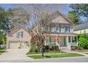 Two-story home with an attached garage, complemented by lush landscaping and an American flag on the porch at 772 Preservation Pl, Mount Pleasant, SC 29464