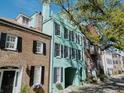 Charming teal townhome with black shutters nestled among historic brick buildings with tree lined street at 12 Elliott St # A, Charleston, SC 29401