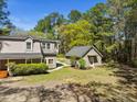 View of a light gray two-story home and separate gray outbuilding on a sunny day with lush landscaping at 1212 Pinopolis Rd, Moncks Corner, SC 29461