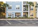 Close-up view of an attractive three-story building with colorful accents and inviting landscaping with palm trees at 2200 Belle Isle Ave # 103, Mount Pleasant, SC 29464