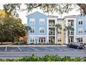 View of a three-story building showcasing blue and yellow accents, palm trees, and convenient parking with a car at 2200 Belle Isle Ave # 103, Mount Pleasant, SC 29464