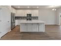 Spacious kitchen with island, stainless appliances, white cabinets, and wood floors at 234 Silk Oak Dr, Moncks Corner, SC 29461
