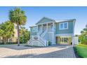 Charming coastal home with a brick driveway, staircase, and lush tropical landscaping at 3419 Myrtle St, Edisto Island, SC 29438