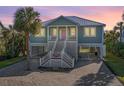 Charming coastal home at sunset with a brick driveway, staircase, and lush tropical landscaping at 3419 Myrtle St, Edisto Island, SC 29438