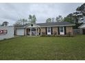 Charming brick home with a manicured lawn, a front porch, and black shutters at 4984 Foxwood Dr, North Charleston, SC 29418
