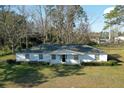 Well-maintained single-story home with white facade, complemented by green shrubbery and mature trees at 6156 Badham Dr, Reevesville, SC 29471