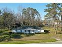 Traditional single-story home with white exterior, complemented by green lawn and mature trees in the background at 6156 Badham Dr, Reevesville, SC 29471
