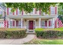 Inviting front porch featuring decorative columns, manicured shrubs, and a charming entryway with patriotic accents at 9360 S Moreto Cir, Summerville, SC 29485
