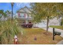Inviting two-story house featuring a well-kept lawn, beautiful landscaping, and a cozy front porch at 9684 Pebble Creek Blvd, Summerville, SC 29485