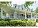 Charming two-story home boasting a welcoming porch, black shutters, and lush landscaping at 1021 Barfield St, Charleston, SC 29492
