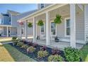 Inviting front porch with hanging plants, rocking chairs, and colorful flower arrangements, perfect for relaxing at 106 Wood Sage Run, Summerville, SC 29485
