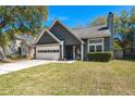 Charming exterior featuring a two-car garage, well-maintained lawn, and classic design under a clear blue sky at 125 Mansfield Blvd, North Charleston, SC 29418