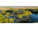Aerial view showcasing a beautiful estate with waterfront access, mature trees, and circular driveway at 1644 Omni Blvd, Mount Pleasant, SC 29466