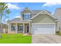 Inviting two-story home featuring a front porch, an attached garage, and a vibrant green lawn at 189 Weeping Cypress Dr, Moncks Corner, SC 29461