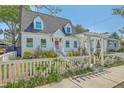 Quaint home showcasing lush landscaping, a decorative white pergola, and a welcoming picket fence at 928 Ashley Ave, Charleston, SC 29403