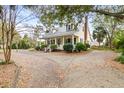 Charming home with a wraparound porch and a spacious driveway amidst a lush, green landscape at 1034 Orangeburg Rd, Summerville, SC 29483