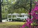 Beautiful white brick home with a covered porch surrounded by lush greenery and blooming azaleas at 107 Woodland Dr, Summerville, SC 29485