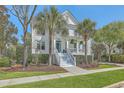 Inviting two-story home surrounded by lush landscaping, including palm trees, and a beautiful blue front door at 1115 Barfield St, Charleston, SC 29492