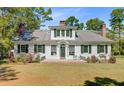 Charming two-story home with white siding, black shutters, mature trees, and manicured lawn at 1300 S Main St, Summerville, SC 29483