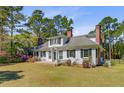 Charming two-story home with white siding, black shutters, mature trees, and manicured lawn at 1300 S Main St, Summerville, SC 29483