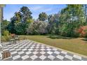 Spacious checkered tile patio surrounded by lush landscaping and mature trees at 1300 S Main St, Summerville, SC 29483