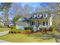 Inviting two-story home with a well-manicured lawn and a cozy front porch framed by vibrant green shrubs at 3447 Toomer Kiln Cir, Mount Pleasant, SC 29466