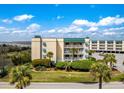 Beautiful condo building features balconies, manicured landscaping, and ocean proximity on a sunny day at 3701 Dock Site Rd # 302, Edisto Beach, SC 29438