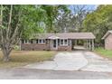 Well-maintained one-story brick home featuring a covered parking area, mature trees, and lawn at 4757 June St, North Charleston, SC 29405