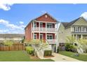 Charming red two-story home with a two-car garage, balconies, manicured lawn, and a private driveway at 490 Sanders Farm Ln, Charleston, SC 29492