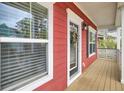Covered front porch featuring red siding, white trim, large windows, and a welcoming glass front door at 490 Sanders Farm Ln, Charleston, SC 29492