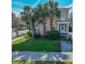Inviting two-story home with a front porch, complemented by well-kept landscaping and mature palm trees at 125 Ashley Ave, Charleston, SC 29401