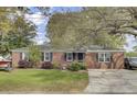 Traditional brick home with well-manicured lawn, mature trees and black shutters on windows at 1406 Iroquois St, North Charleston, SC 29405