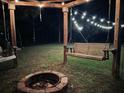 Backyard at dusk featuring a fire pit and swing illuminated with string lights at 1433 Oakhurst Dr, Mount Pleasant, SC 29466