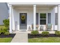Inviting front porch with seating, lovely landscaping, and a welcoming yellow wreath at 1586 Innkeeper Ln, Johns Island, SC 29455