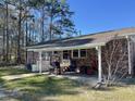 Inviting covered back patio featuring a grill, comfortable seating, and a well-manicured lawn at 260 Carolina Cir, Walterboro, SC 29488