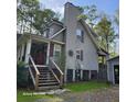 A look at the home's rear, featuring stairs and wood construction in a partially wooded lot at 2729 Barracada Rd, Walterboro, SC 29488