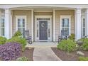 Inviting front porch featuring rocking chairs, elegant columns, and a beautifully decorated front door at 145 Billowing Sails St, Summerville, SC 29486