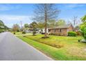 Suburban street featuring a traditional brick home with a green lawn and mature trees at 1515 Wakendaw Rd, Mount Pleasant, SC 29464