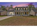 Charming two-story home featuring a welcoming front porch and solar panels on the roof at dusk at 176 Hainsworth Dr, North Charleston, SC 29418
