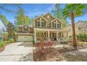 Traditional two-story home featuring a cozy front porch, two-car garage, palm tree, and driveway at 1883 Hall Point Rd, Mount Pleasant, SC 29466