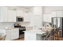 Bright, white kitchen with stainless steel appliances, island with bar seating, and ample cabinet space at 203 Belfort Pl, Summerville, SC 29486