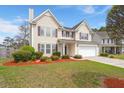 Charming two-story home with tan siding, dark shutters, a well-manicured lawn, and an attached two-car garage at 210 Sabal Palmetto Ct, Moncks Corner, SC 29461