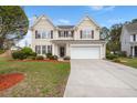 Charming two-story home with tan siding, dark shutters, a well-manicured lawn, and an attached two-car garage at 210 Sabal Palmetto Ct, Moncks Corner, SC 29461