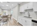 Bright kitchen featuring white cabinets, stainless steel sink, and an adjacent dining area with wood flooring at 2325 Sorentrue Ave, North Charleston, SC 29405