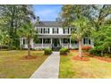 Inviting two-story home with a classic porch, well-manicured lawn, and mature palm trees enhancing curb appeal at 516 Central Ave, Summerville, SC 29483