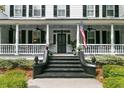Inviting front porch features classic railing, black stairs, elegant decor, and an American flag at 516 Central Ave, Summerville, SC 29483